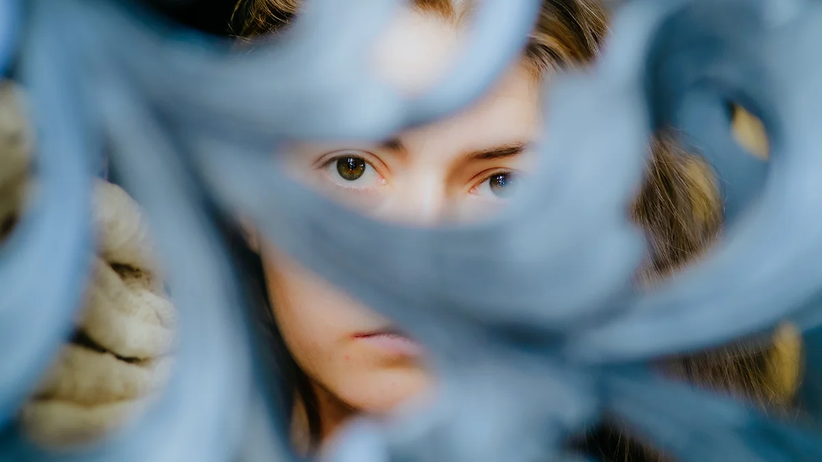 A woman with beautiful eyes but thin lashes looking through a fence
